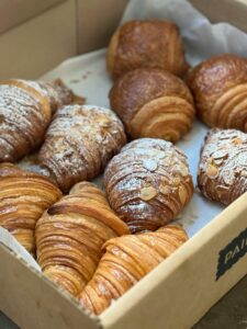 A tempting selection of homemade croissants and pastries in a bakery box.